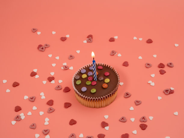 粉色背景上有蜡烛的松饼。假日松饼。图片下载