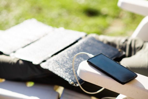 这款手机是由太阳能电池充电的。太阳能电池在一个不认识的人的腿上。图片下载