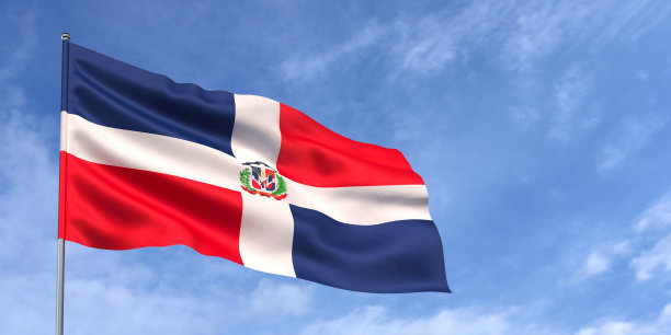 蓝天背景下旗杆上的多米尼加国旗。多明尼加国旗在风中飘扬，背景是有云的天空。发短信的地方。3 d演示。图片下载