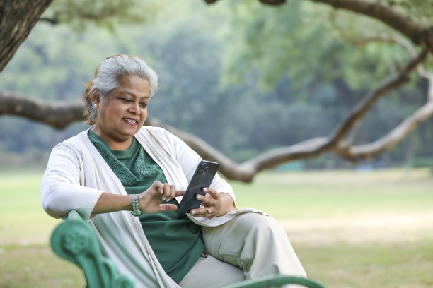 印度老年妇女在公园使用智能手机。图片下载
