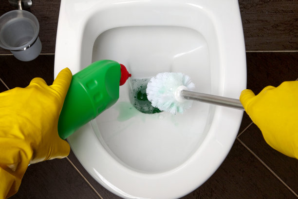一个戴着黄色橡胶手套的人用刷子和消毒剂清洁抽水马桶图片下载