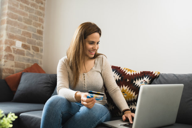 一个快乐的年轻女子的肖像享受在家里和网上购物图片下载