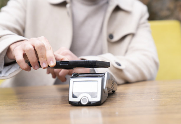 特写:一名男性在咖啡馆用智能手机用信用卡非接触式支付支付账单，在卡机上扫描。电子支付。银行和科技图片下载