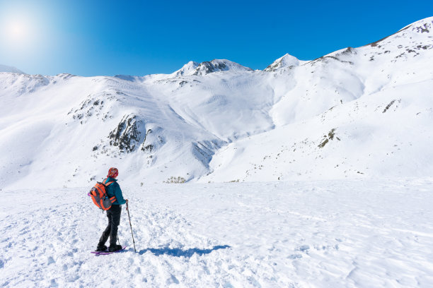 穿着登山装备的女子凝视着雪山的景色图片下载
