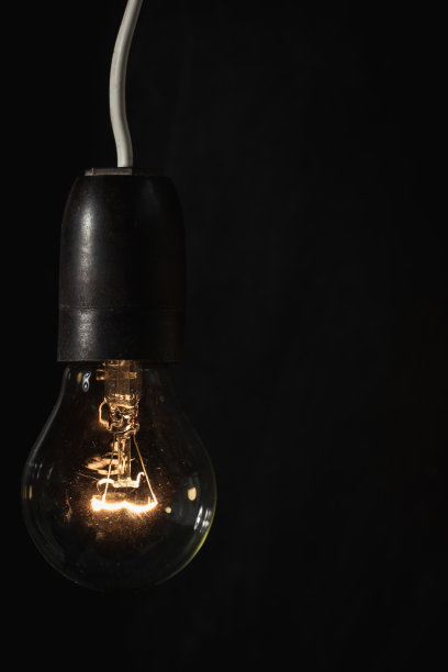 点燃白炽灯与钨丝发光的黑色背景与文本复制空间。节约能源的概念。能源危机图片下载
