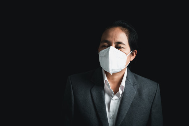 女性佩戴N95 PM 2.5呼吸防护口罩，防止空气污染和粉尘颗粒超过安全限度。健康、环保、生态理念。过敏、头痛。城市空气危险。图片下载