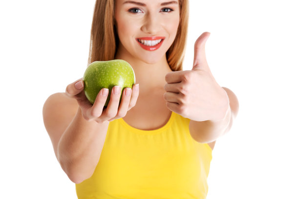漂亮的白人女士，金发，拿着一个苹果，竖起大拇指图片下载
