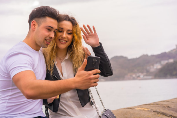 可爱的幸福夫妇享受假期，旅行和自拍通过智能手机图片下载