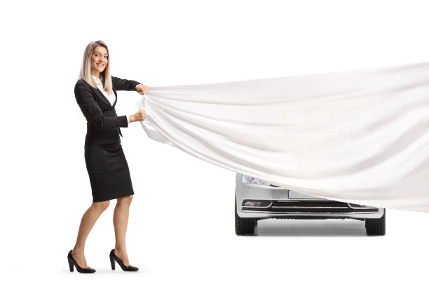 女商人在一辆新的银色汽车前拉着一块白色的布图片下载