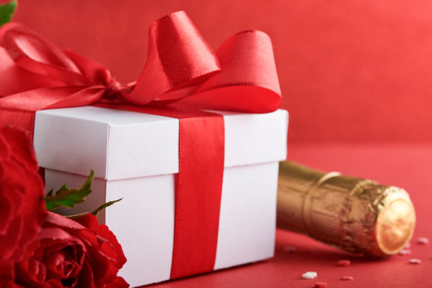 浪漫晚餐概念。浪漫的餐桌，银器，酒杯，礼品盒，玫瑰和象征爱情的红色背景红心。情人节、婚礼、生日、妇女和母亲节。图片下载