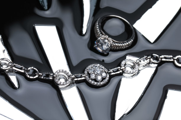 奢华的珠宝。时尚的介绍优雅的戒指和手镯在黑色镜子表面与碎玻璃图片下载