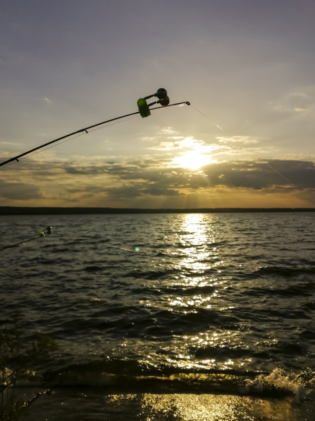 日落垂钓。夕阳下的钓竿。夕阳下的钓鱼竿。晚上钓鱼。图片下载