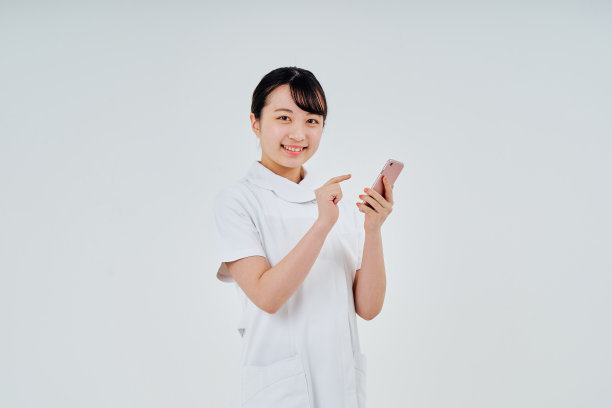 一名身穿白大褂的女子正在操作智能手机图片下载