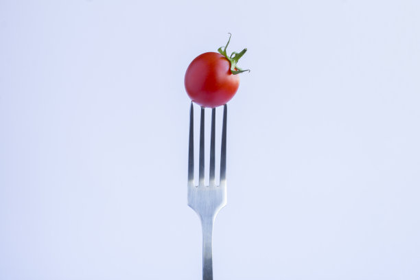樱桃番茄插在白色背景的银叉上。特写镜头。副本的空间。图片下载