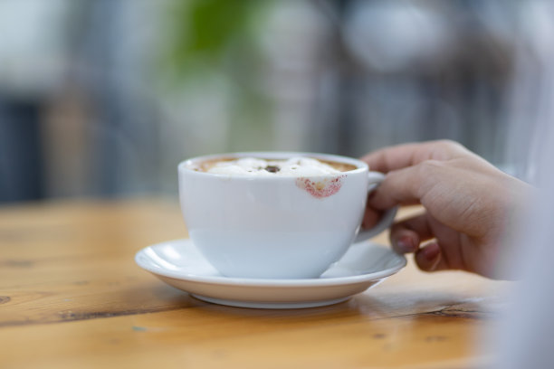 咖啡杯上有口红渍。女人拿着咖啡杯在早上喝咖啡。图片下载