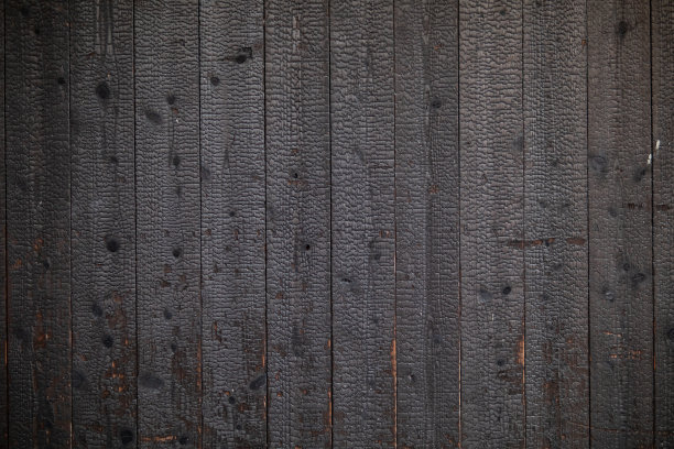 燃烧木材碳化后形成的黑色木墙背景，表面呈黑色，看起来很自然，用作装饰墙，使建筑看起来不寻常。图片下载