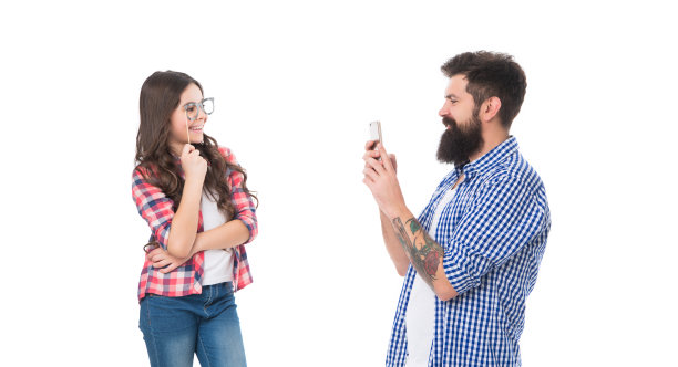 对着镜头微笑。戴着展台眼镜的女孩为智能手机摆姿势。智能手机摄影图片下载