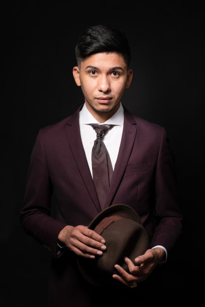 白人男子在西装拿着一顶帽子在黑暗的背景图片下载