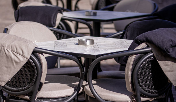 在一个欧洲城市的鹅卵石巷子里，午餐时间之外的空桌子，一个阳台，一个咖啡馆，春天图片下载