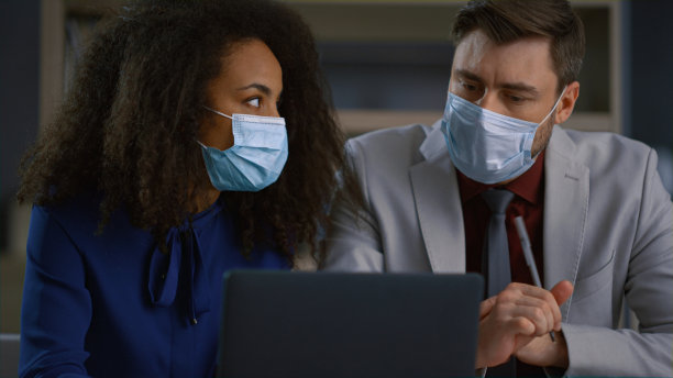 不同的商务人士戴着口罩在新冠办公室的笔记本电脑上在线分析数据图片下载