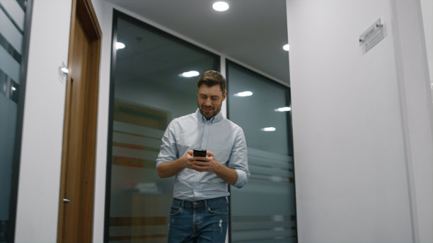 微笑的经理独自走在办公室，在商务中心打电话。图片下载