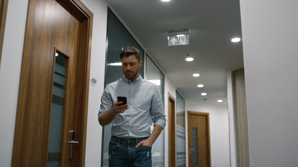 成功的商人走在办公室走廊打电话。工作的概念。图片下载