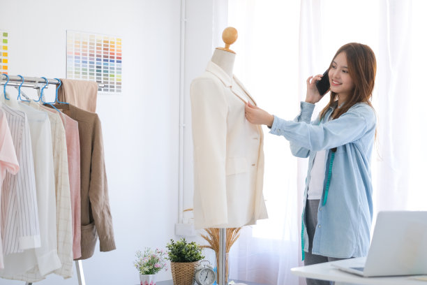 年轻的亚洲女性职业时装设计师正在电话中与客户谈论工作细节。图片下载