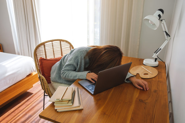 一名年轻女子在家里用笔记本电脑工作时累了，在办公桌前睡着了图片下载