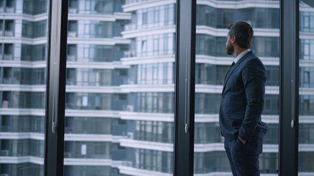 企业家走过公司大楼。商人在办公室里看窗户。图片下载