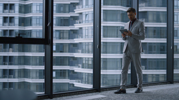 专注的企业家使用平板电脑在办公大楼研究公司数据。图片下载