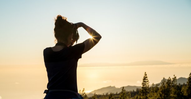 女人的剪影与相机。一名女子在夕阳下拍摄拉戈梅拉岛的照片。特内里费岛。图片下载