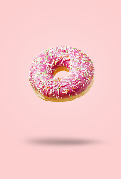 美味的甜甜圈，粉红色的背景上有零星的糖屑。现代食品概念。糕点店，咖啡馆的广告。图片下载