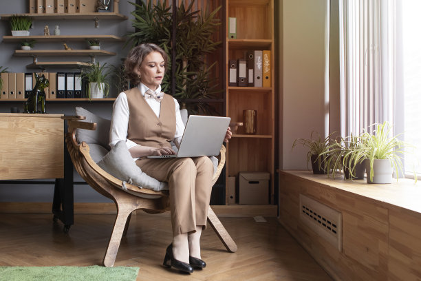 身着米色西装的商务女士在办公室工作，正在电脑上打字图片下载