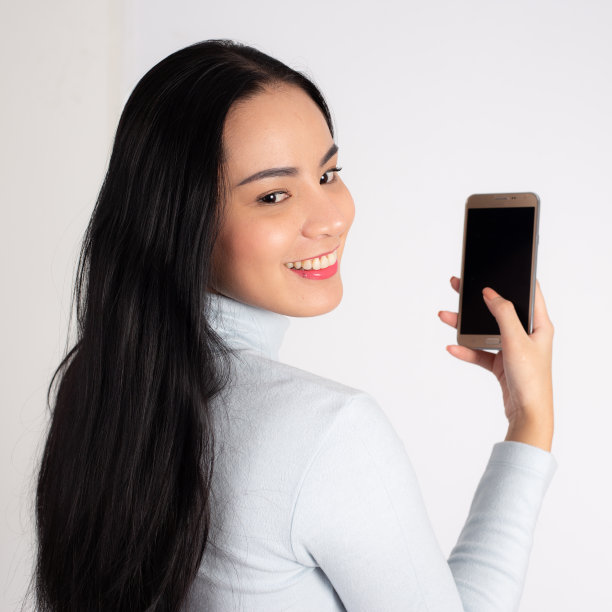 一名女子背对着站着，在白色背景下使用手机图片下载