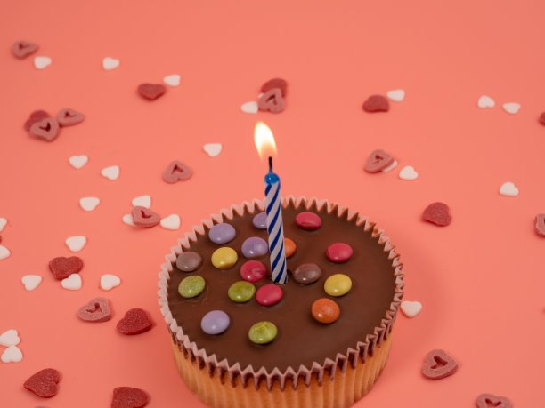 粉色背景上有蜡烛的松饼。假日松饼。图片下载