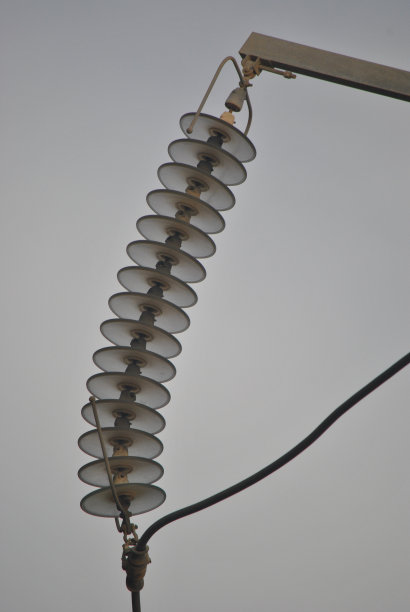 灰色天空下的电力线绝缘子，玻璃材质工业电力概念图片下载