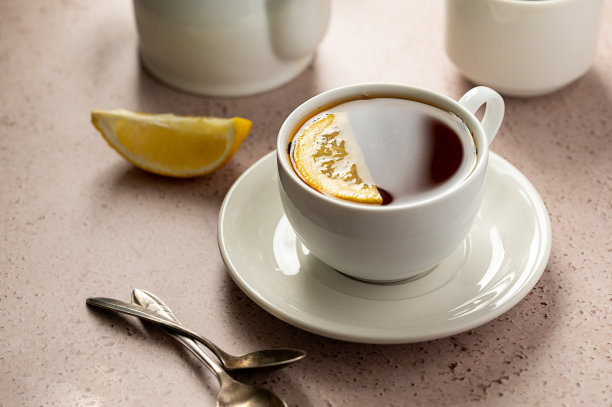 喝茶。白色陶瓷杯，盛红茶和柠檬片。中性的背景。图片下载