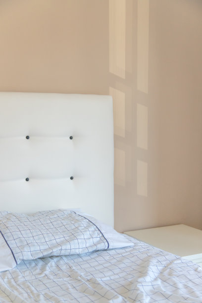 明亮的卧室内部细节，有枕头和床头板，非常舒适，舒适和现代，光线穿过墙壁。白色和柔和的色调。本空间图片下载