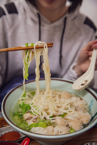 饥饿的顾客用筷子夹起美味的馄饨汤面图片下载