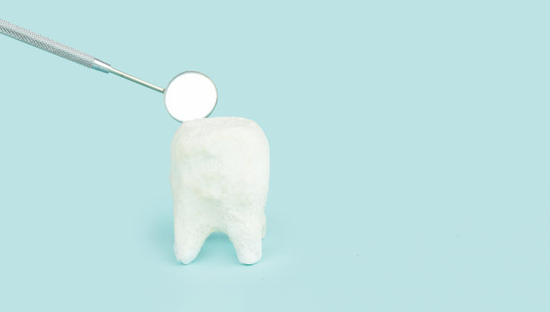 蓝色背景上的牙医嘴镜的白色牙齿模型的特写。图片下载