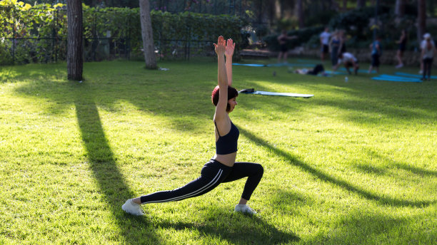一位穿着运动服的黑发成年女子在酒店的绿地上进行上午的课程图片下载