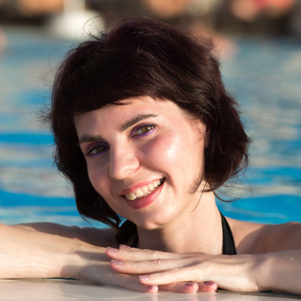在游泳池的背景上，一个褐发女人的脸带着微笑图片下载