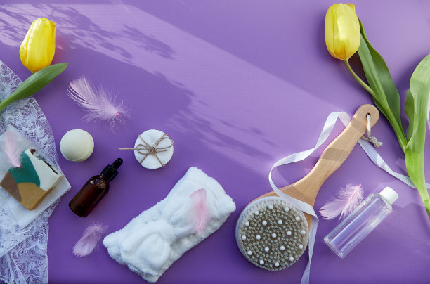 健康和SPA美容护理完整:卫生配件，天然肥皂，精油，按摩刷，浴弹，紫色背景郁金香海绵。本空间图片下载