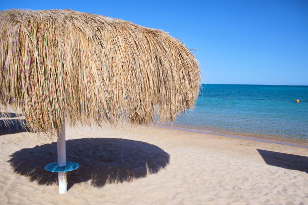 热带海洋地区的稻草遮阳伞，在夏天的蓝色充满活力的天空图片下载