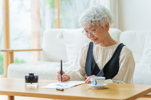 一位年长的亚洲妇女在客厅里写书法图片下载