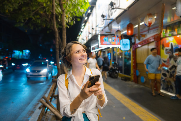 一个拿着智能手机的女人晚上走在城市里图片下载