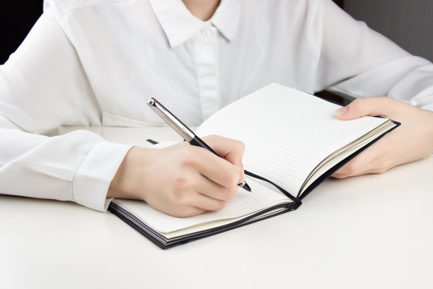 一个小女孩在笔记本上写字。在白色的桌子旁图片下载