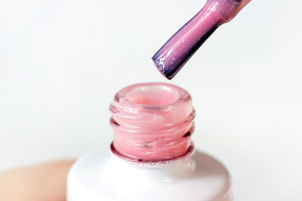 粉彩粉红色的希拉克指甲油从刷子倒进瓶子在浅背景接近图片下载
