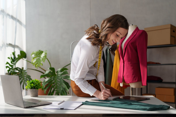 年轻漂亮的专业设计师在设计工作室室内工作。时装设计师概念图片下载