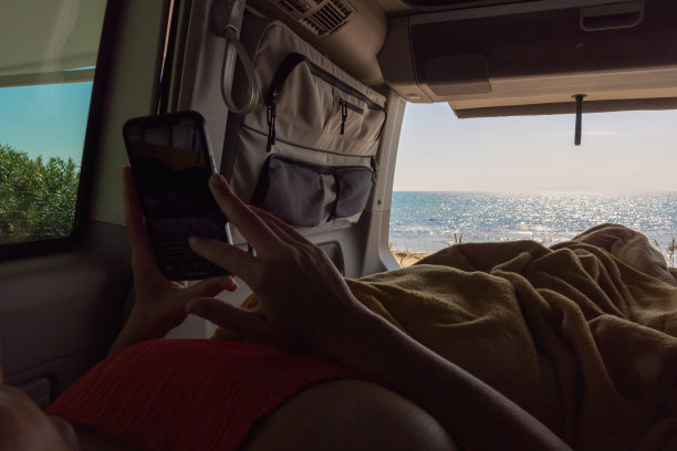 暑假期间，一名女子在露营车里使用智能手机图片下载